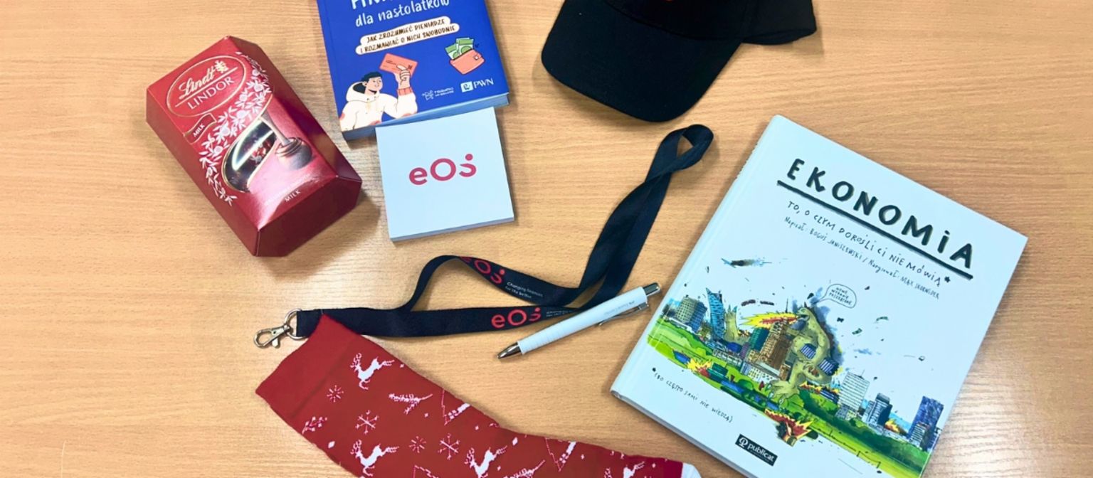 Miejsce pracy z materiałami EOS na warsztaty edukacji finansowej w Polsce – broszury, zeszyty i artykuły biurowe na drewnianym biurku