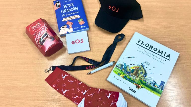 Miejsce pracy z materiałami EOS na warsztaty edukacji finansowej w Polsce – broszury, zeszyty i artykuły biurowe na drewnianym biurku