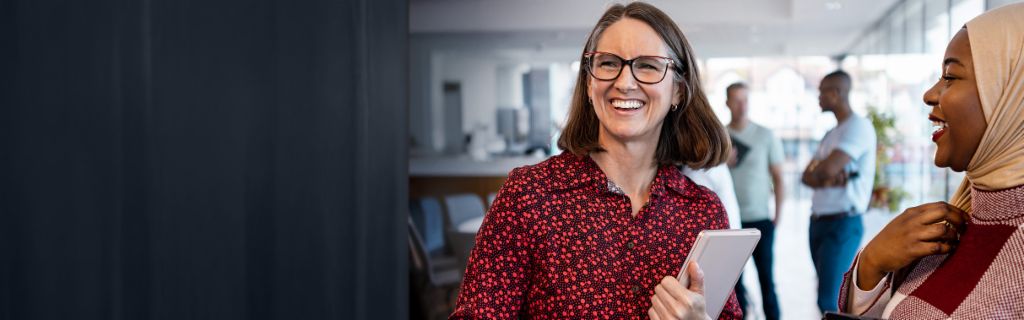 Dwie szczęśliwe kobiety rozmawiają swobodnie w biurze