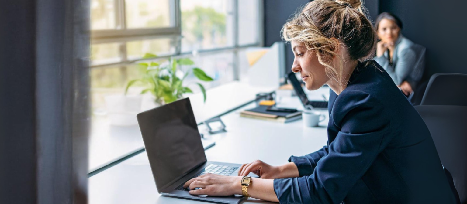 Young woman is working on a laptop in a modern office.