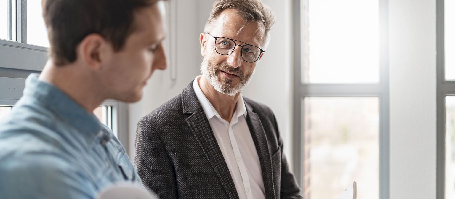 Dwóch mężczyzn w biurze wymienia się pomysłami na temat dokumentów roboczych dotyczących cyfryzacji.
