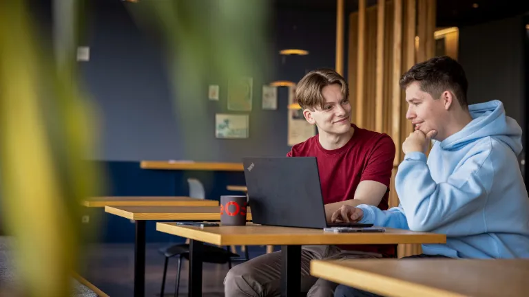 Dwoje pracowników współpracuje przy laptopie, promując partnerstwo i sprawiedliwość w miejscu pracy.