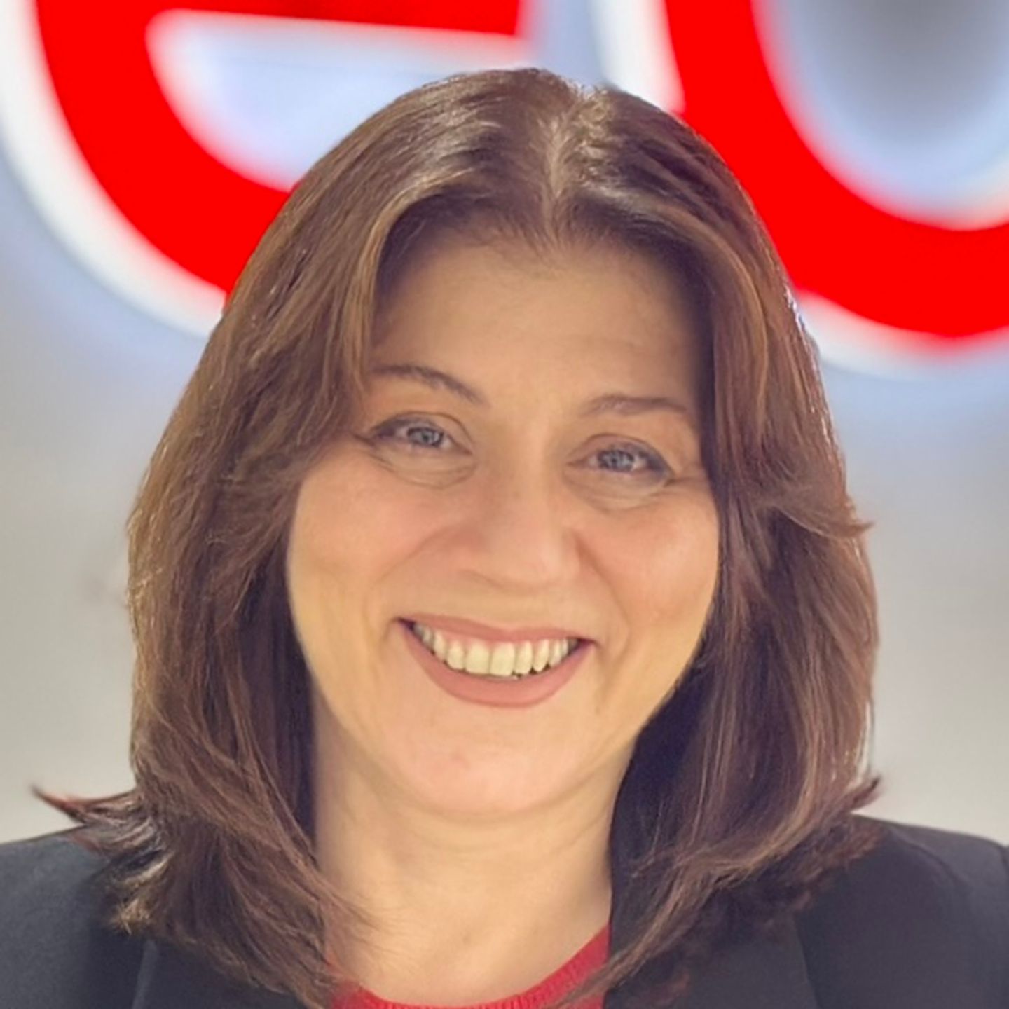 Belén Barreiro, agentka Contact Center w EOS w Hiszpanii, opiera się o ladę w czarnym blezerze przed jasnym logo EOS.