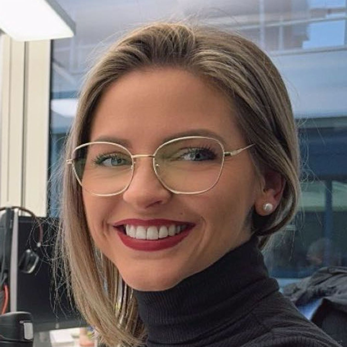 Genny Bollinger, specjalistka ds. restrukturyzacji zadłużenia w EOS w Szwajcarii, siedzi przy biurku w szarym golfie i uśmiecha się do kamery.