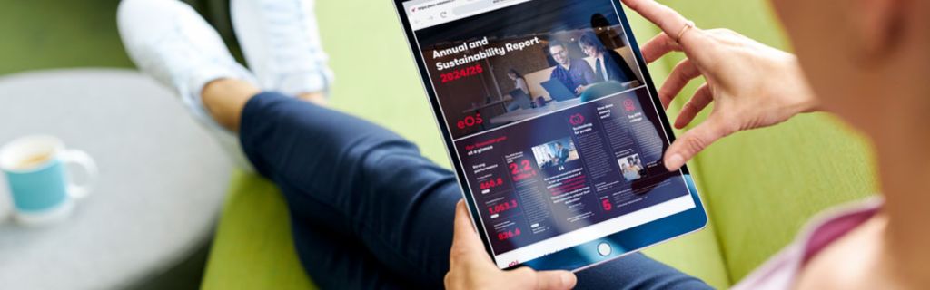 Osoba na zielonej kanapie przeglądająca Raport Roczny i Raport Zrównoważonego Rozwoju EOS 2024/25 na tablecie