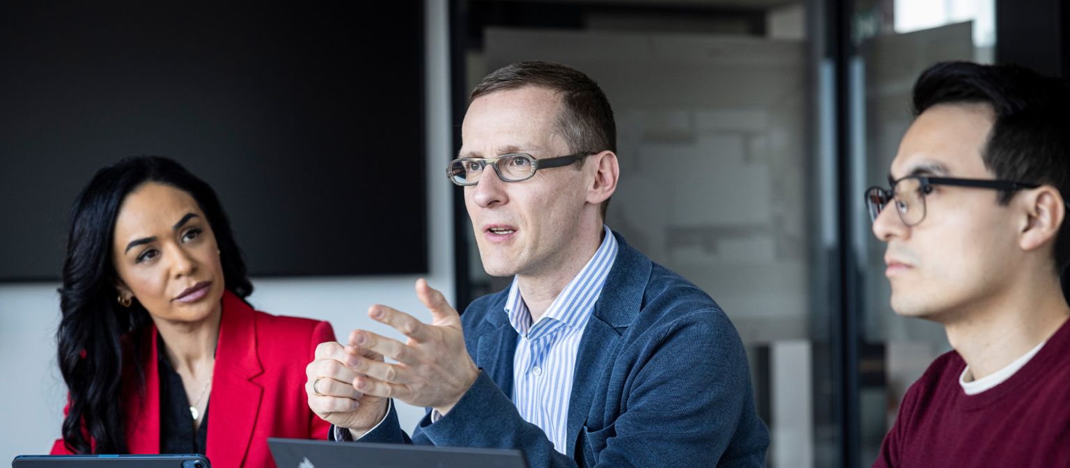 Trzy osoby rozmawiają w biurze.