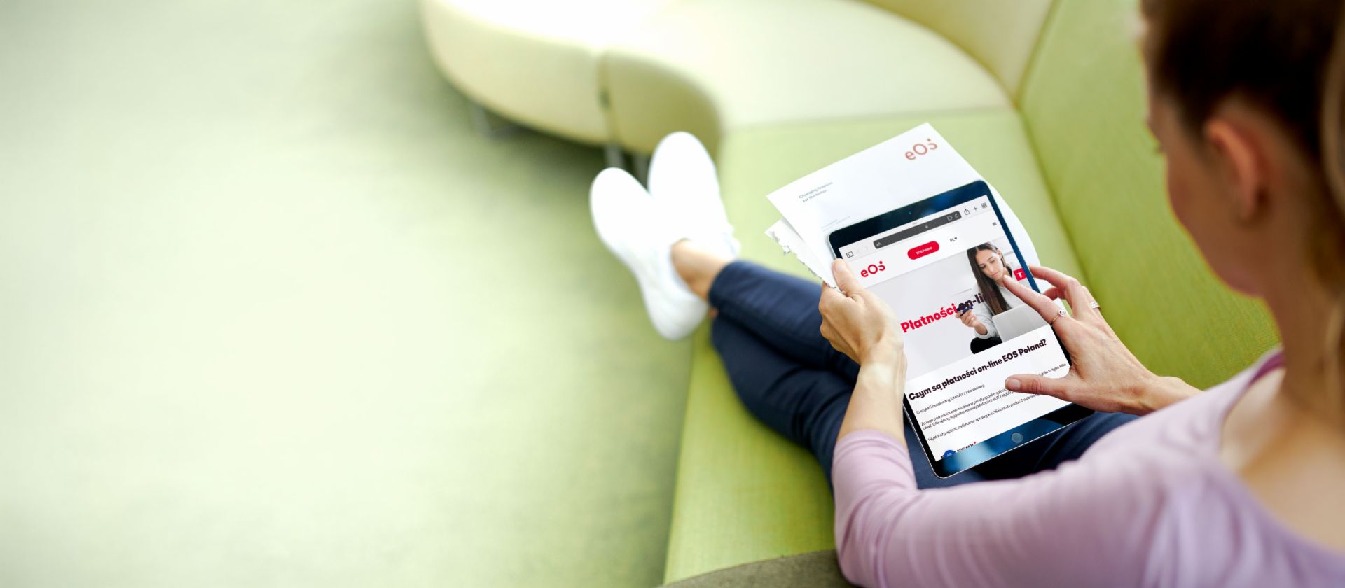 Kobieta korzysta z portalu internetowego EOS na tablecie, aby spłacić zaległe długi z wygodnej kanapy.