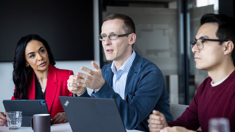 Trzy osoby rozmawiają w biurze.